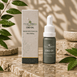 Premium lifestyle image of Pure CBD4U Broad Spectrum CBD Oil 10% 1000mg in a luxurious wellness setting with natural leaves, water droplets and elegant stone elements. Original 10ml bottle and packaging displayed with a sophisticated premium appearance.